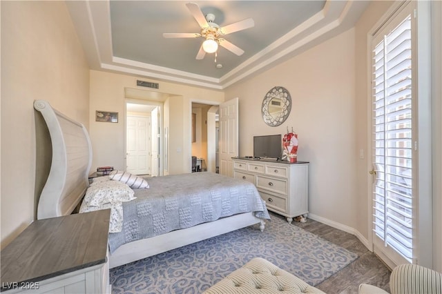 bedroom with a raised ceiling, ceiling fan, and multiple windows