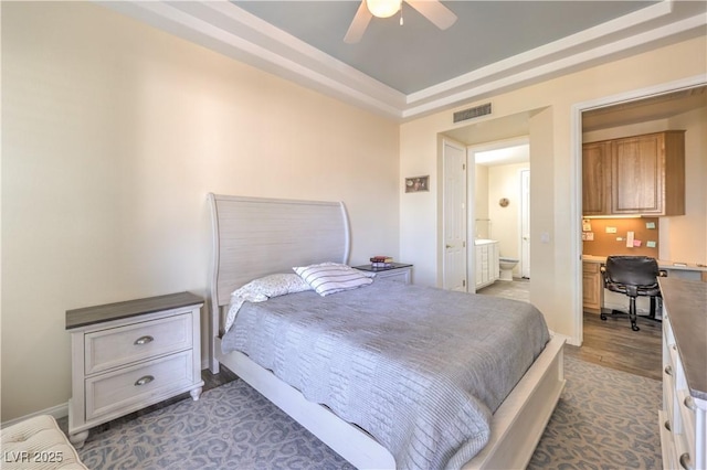 bedroom with ceiling fan, dark hardwood / wood-style flooring, built in desk, and a raised ceiling