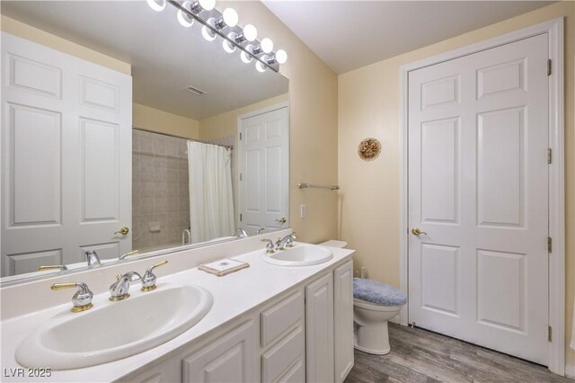 bathroom with hardwood / wood-style flooring, vanity, toilet, and walk in shower