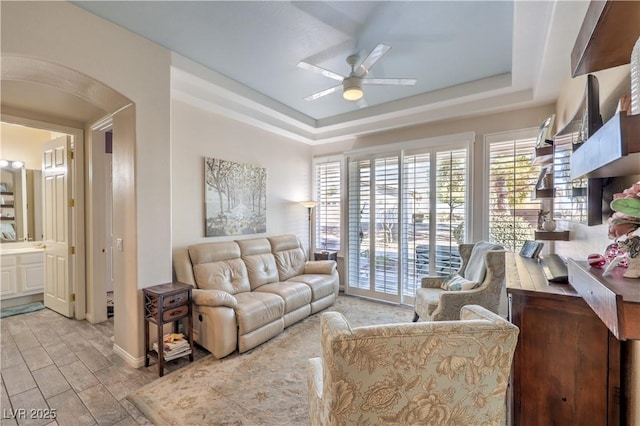 living room with a tray ceiling and ceiling fan