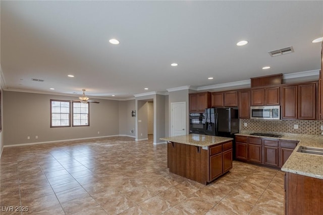 kitchen featuring light stone counters, backsplash, black appliances, and a kitchen island