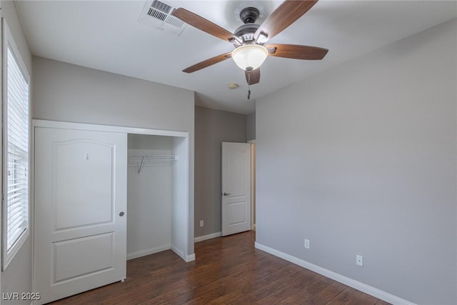 unfurnished bedroom with ceiling fan, dark hardwood / wood-style floors, and a closet