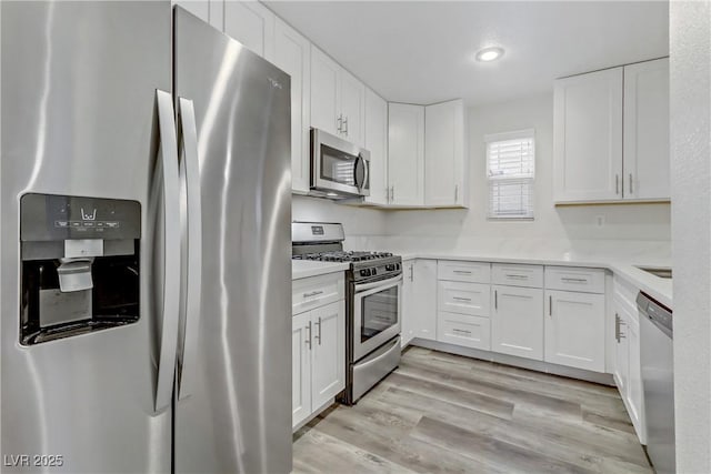 kitchen featuring stainless steel appliances, white cabinets, and light wood-type flooring