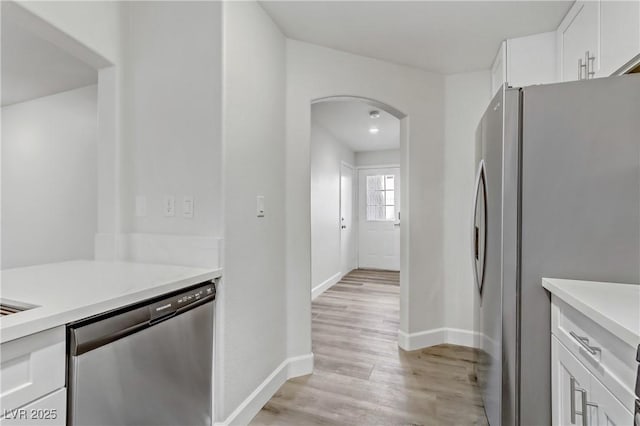 kitchen with light wood-type flooring, white cabinets, and appliances with stainless steel finishes