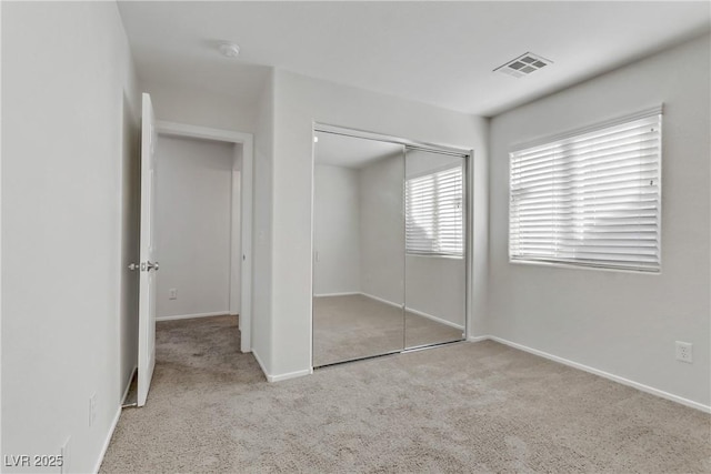 unfurnished bedroom featuring light colored carpet and a closet