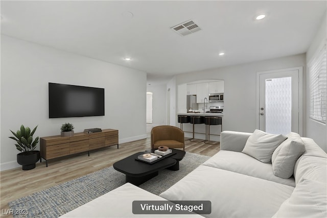 living room with sink and light wood-type flooring