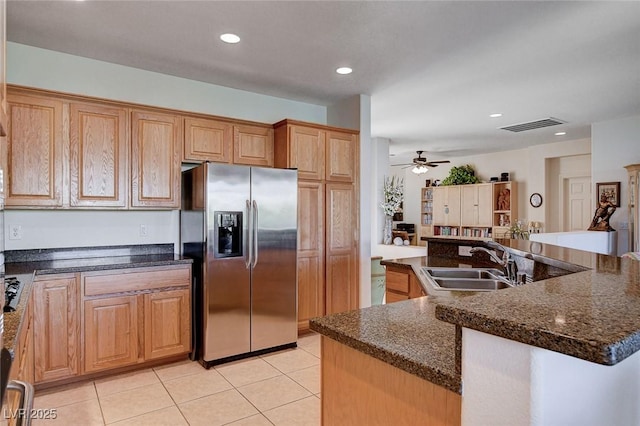 kitchen with sink, ceiling fan, stainless steel refrigerator with ice dispenser, an island with sink, and light tile patterned flooring