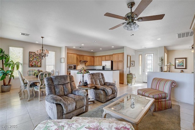 tiled living room with ceiling fan with notable chandelier