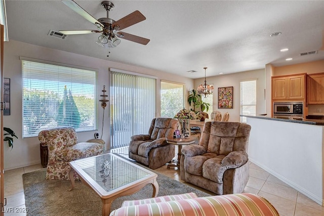 living room with ceiling fan with notable chandelier and light tile patterned floors