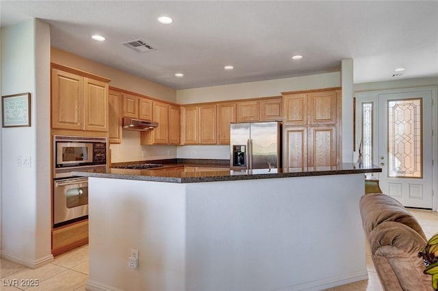 kitchen with stainless steel appliances, light brown cabinetry, a kitchen island, and light tile patterned floors