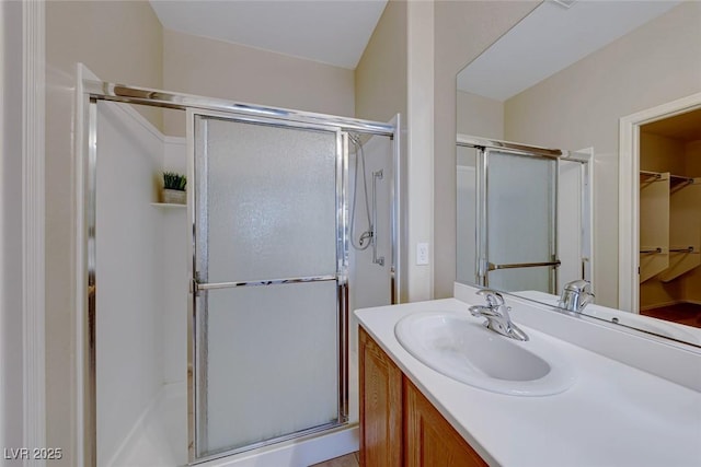 full bathroom with a shower stall, vanity, and a spacious closet