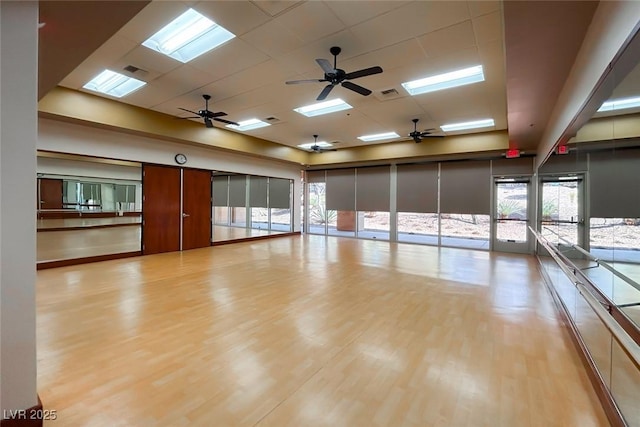 exercise area featuring a paneled ceiling, a skylight, visible vents, and wood finished floors