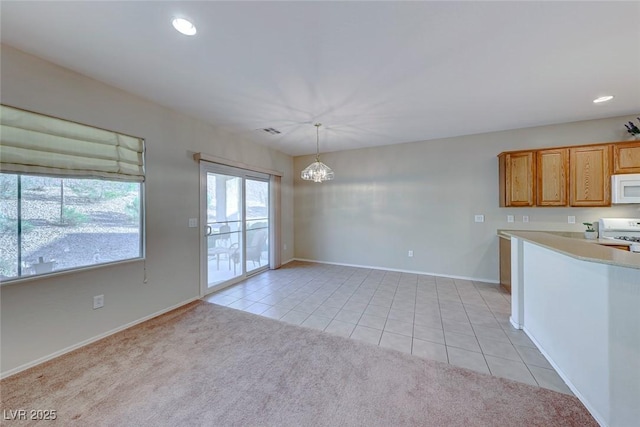 kitchen featuring range, light colored carpet, white microwave, light countertops, and light tile patterned flooring