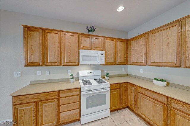 kitchen with white appliances, light tile patterned floors, brown cabinets, light countertops, and recessed lighting