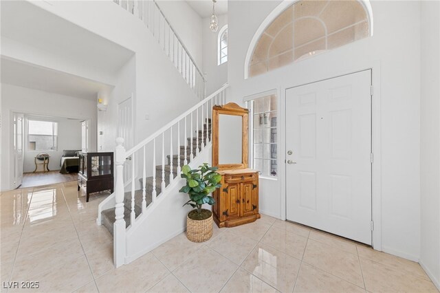 entryway with light tile patterned floors, a towering ceiling, plenty of natural light, and a notable chandelier