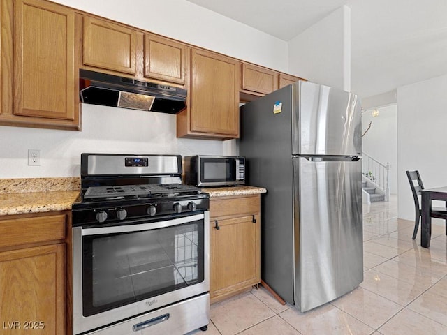 kitchen featuring light tile patterned flooring, appliances with stainless steel finishes, and light stone counters