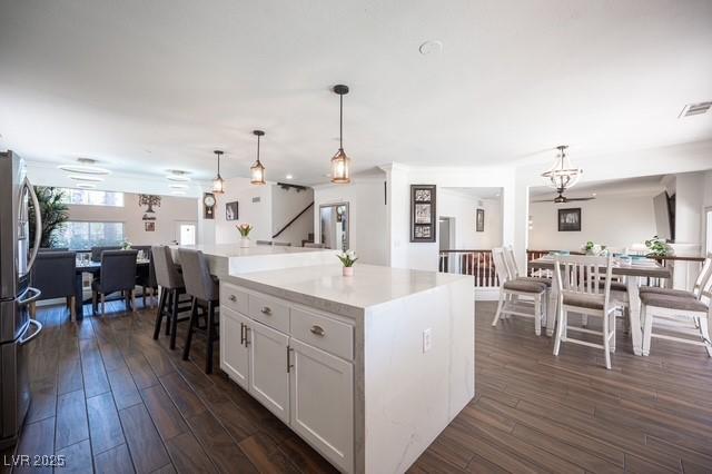 kitchen featuring hanging light fixtures, white cabinetry, a center island, and dark wood-type flooring