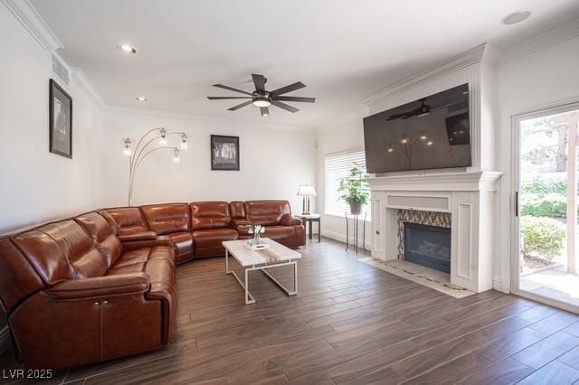 living room with crown molding, dark hardwood / wood-style floors, a high end fireplace, and ceiling fan