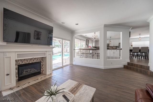 unfurnished living room featuring a chandelier, ornamental molding, a tiled fireplace, and hardwood / wood-style floors