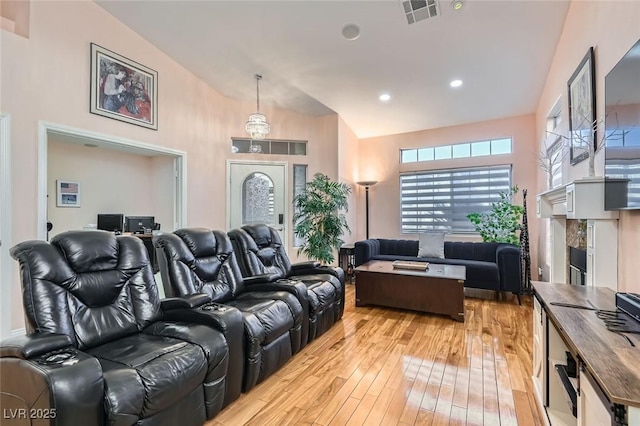 home theater room featuring high vaulted ceiling and light hardwood / wood-style floors