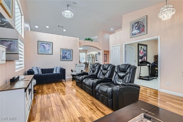 living room featuring an inviting chandelier, light hardwood / wood-style flooring, and a high ceiling