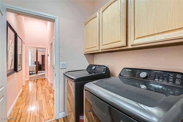 washroom with cabinets, light hardwood / wood-style flooring, and washing machine and clothes dryer