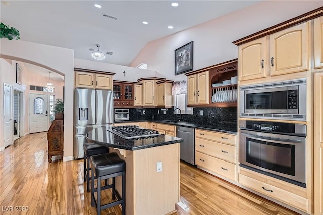 kitchen featuring sink, a breakfast bar, backsplash, stainless steel appliances, and a center island