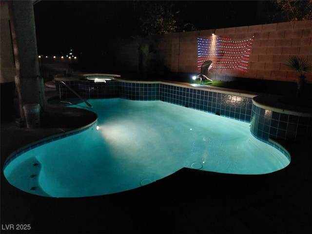 pool at night with an in ground hot tub