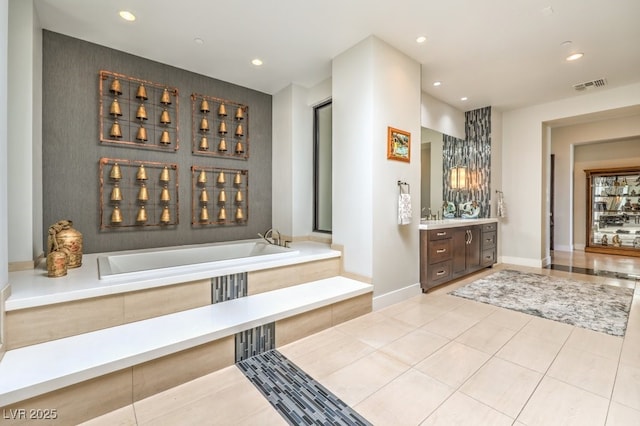 bathroom with a relaxing tiled tub, vanity, and tile patterned floors