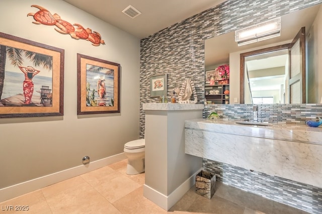 bathroom featuring tile patterned flooring, vanity, decorative backsplash, and toilet