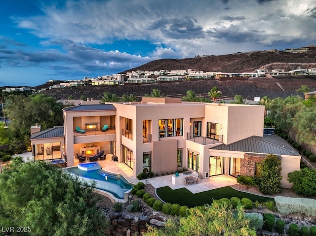 back of property with a mountain view and a patio area