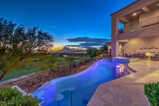 pool at dusk featuring an in ground hot tub, a mountain view, and a patio