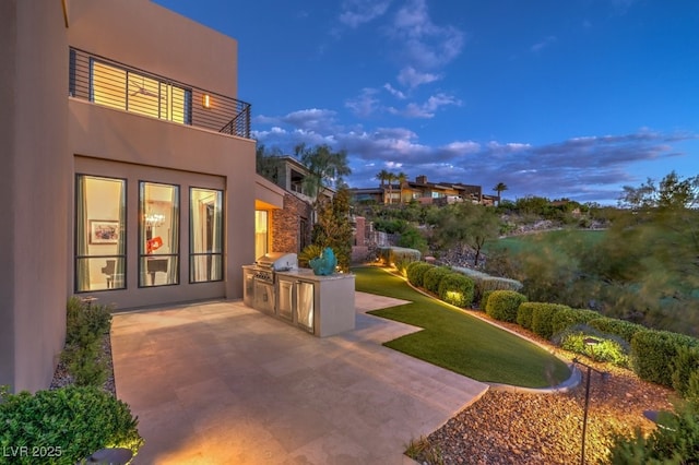 patio terrace at dusk featuring a grill, area for grilling, and a lawn