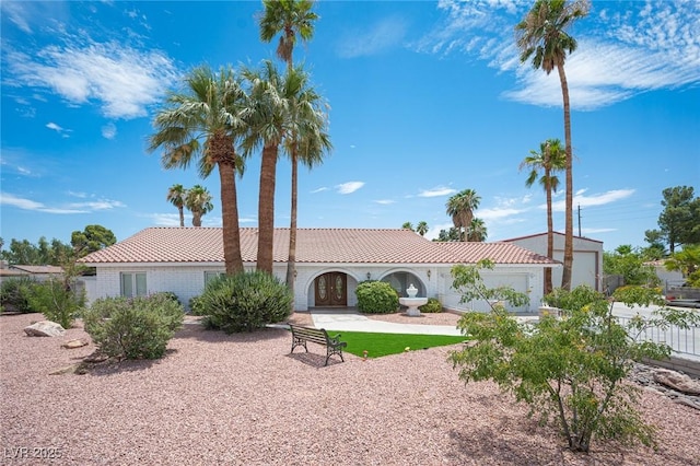 mediterranean / spanish house with an attached garage, a tile roof, and fence