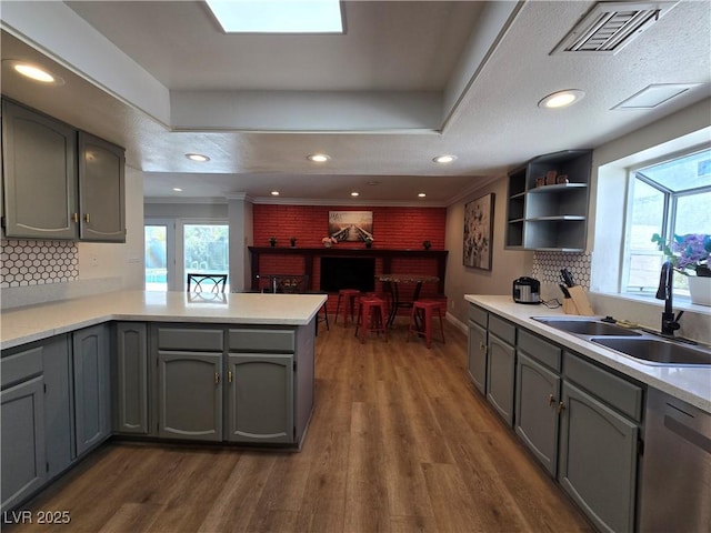 kitchen featuring visible vents, dishwasher, dark wood-style flooring, gray cabinets, and a sink