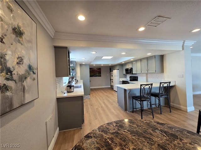 kitchen featuring black range with electric cooktop, gray cabinetry, visible vents, stainless steel microwave, and crown molding