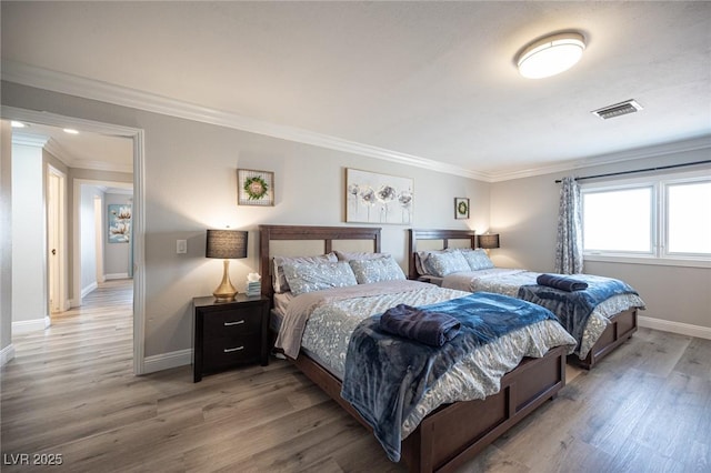 bedroom featuring light wood-type flooring, visible vents, crown molding, and baseboards