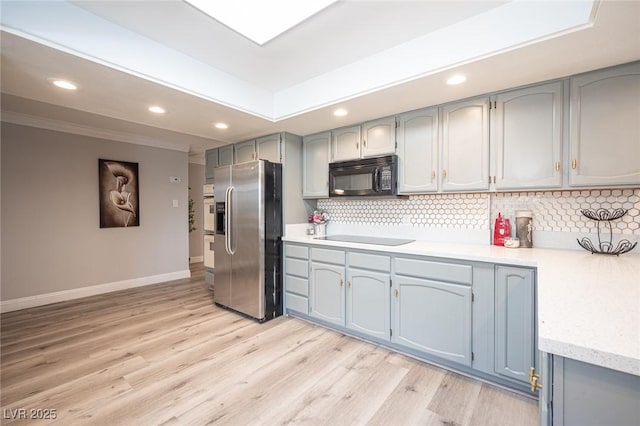 kitchen with tasteful backsplash, recessed lighting, light wood-style floors, black appliances, and baseboards