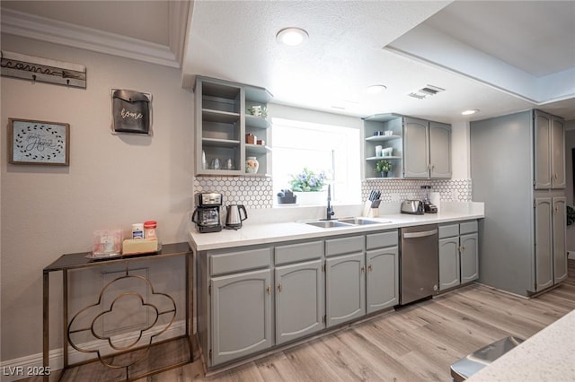 kitchen featuring light wood finished floors, gray cabinets, stainless steel dishwasher, open shelves, and a sink