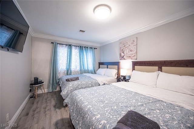 bedroom with ornamental molding, visible vents, baseboards, and wood finished floors