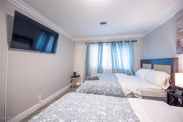 bedroom featuring baseboards, visible vents, crown molding, and wood finished floors