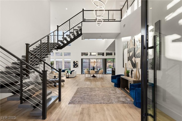 entrance foyer with an inviting chandelier, a towering ceiling, and wood-type flooring