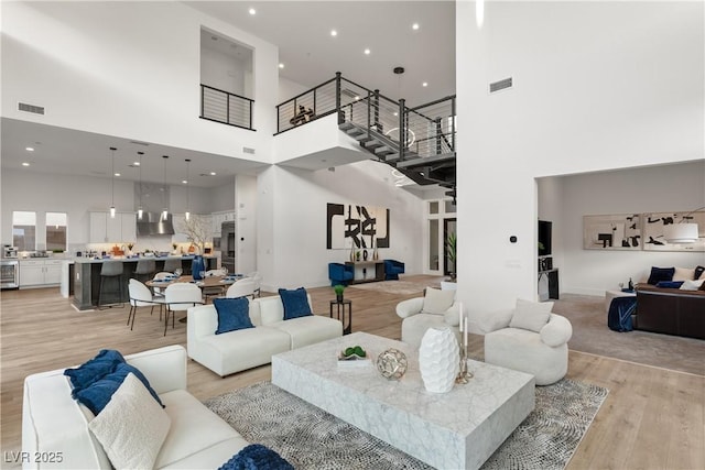 living room with a towering ceiling and light hardwood / wood-style floors