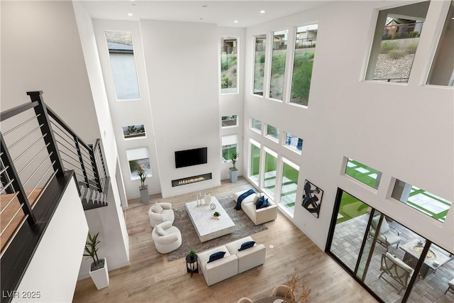 living room featuring a wealth of natural light, wood-type flooring, and a towering ceiling