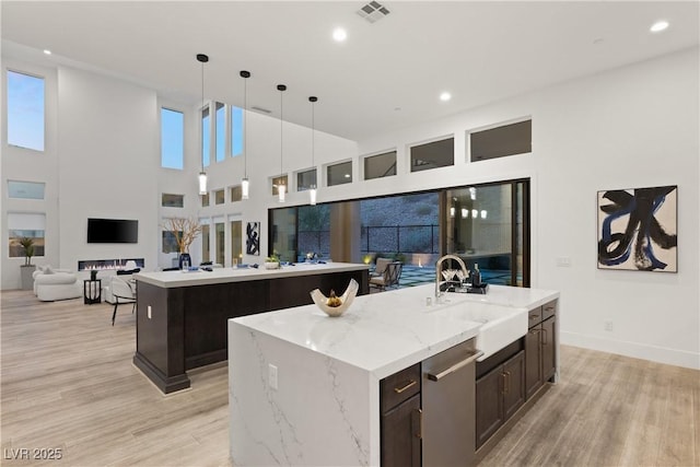 kitchen featuring light hardwood / wood-style flooring, sink, a center island with sink, and decorative light fixtures