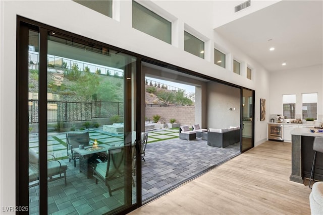 entryway with a towering ceiling, beverage cooler, and light hardwood / wood-style floors