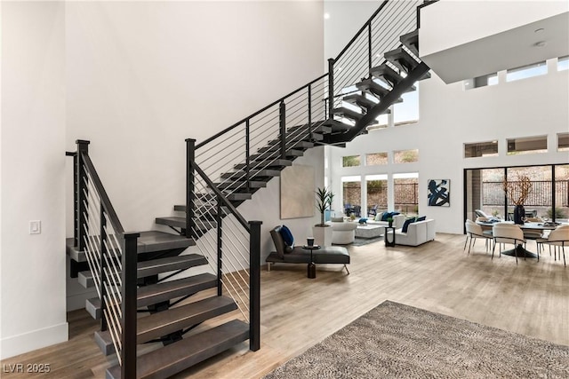 stairway with hardwood / wood-style flooring and a high ceiling