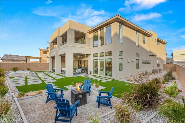 rear view of house featuring central AC unit, a patio area, and an outdoor fire pit