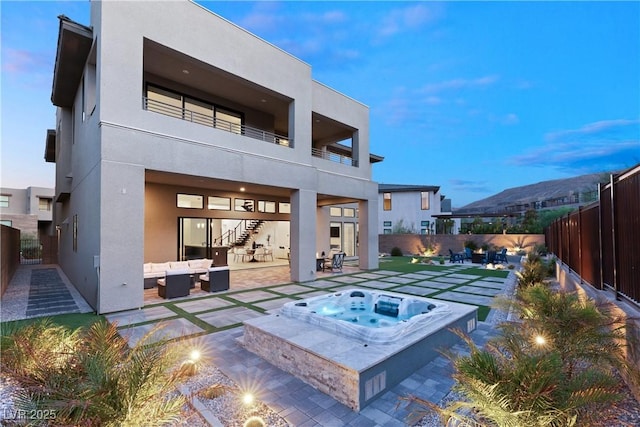 back house at dusk featuring an in ground hot tub, a mountain view, an outdoor hangout area, and a patio