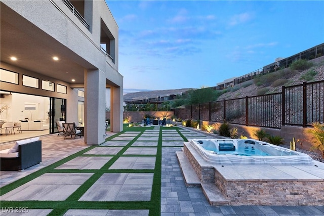 pool at dusk with an outdoor hot tub, a mountain view, and a patio